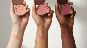 Trois mains présentant des blushs et leurs swatches sur des peaux claires, moyennes et foncées. Gamme de teintes pour diverses carnations.