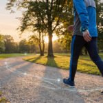Vue d'un homme marchant sur un sentier en gravier dans un parc au coucher du soleil, avec un suivi numérique de ses pas.