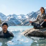 Deux personnes pratiquent la méthode Wim Hof: un bain froid dans un lac gelé et une méditation en montagne enneigée.