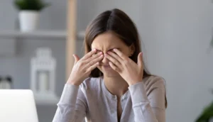 Femme se mettant les doigt sur les yeux à cause d'une migraine